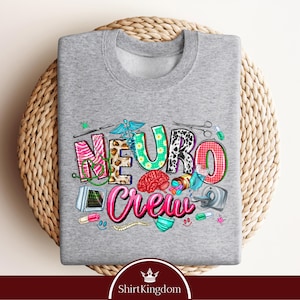 A gray sweatshirt with a colorful graphic design featuring the word "Neuro Crew" surrounded by various medical and healthcare-related icons.