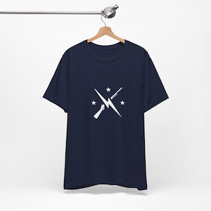 May include: A navy blue t-shirt with a white graphic of a lightning bolt and two crossed guns. The graphic also includes four white stars.