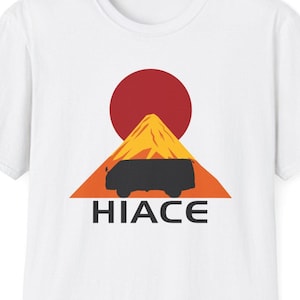 May include: White t-shirt featuring a graphic of a black van driving up a mountain with a red sun behind it. The text "HIACE" is printed below the van.