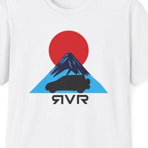 May include: White t-shirt with a graphic of a black car driving in front of a blue mountain with a red sun behind it. The text "RVR" is printed below the car.