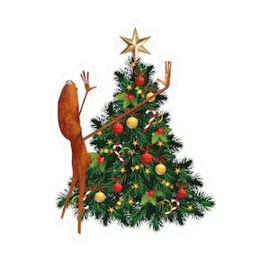 May include: A sticker featuring a Christmas tree decorated with red and gold ornaments, candy canes, and a gold star on top. A brown, cartoonish creature with outstretched arms is positioned next to the tree, as if admiring it.