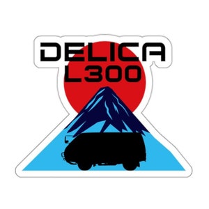 Op de afbeelding: Een sticker met een zwart silhouet van een bestelwagen voor een blauwe en witte berg met een rode zon erachter. De tekst "DELICA L300" staat boven de berg.