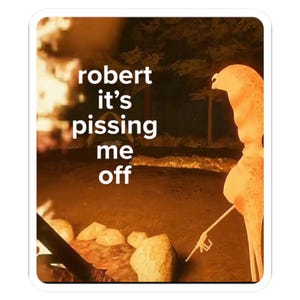 May include: A sticker with a campfire scene. The text "robert it's pissing me off" is in white block letters. A person-shaped figure is silhouetted in orange, holding a lighter. The background shows trees and a fire.