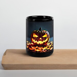 Könnte beinhalten: Schwarze Keramik-Tasse mit einem leuchtenden Kürbis-Design. Der Kürbis hat ein geschnitztes Gesicht mit leuchtend gelben Augen und einem grinsenden Mund. Die Tasse ist mit kleineren Kürbisgesichtern am Boden verziert.