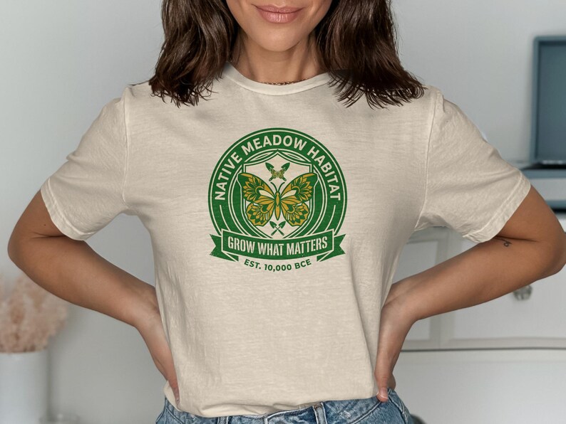 Cream t-shirt with green circular logo "Native Meadow Habitat Grow What Matters Est. 10,000 BCE".
