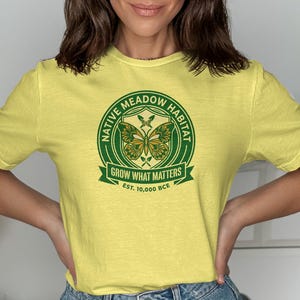 Yellow t-shirt with green Native Meadow Habitat logo featuring butterflies and text.