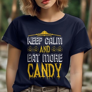May include: A navy blue t-shirt with a Halloween-themed design. The text on the shirt reads "Keep Calm and Eat More Candy" with a crown and pumpkin illustrations.