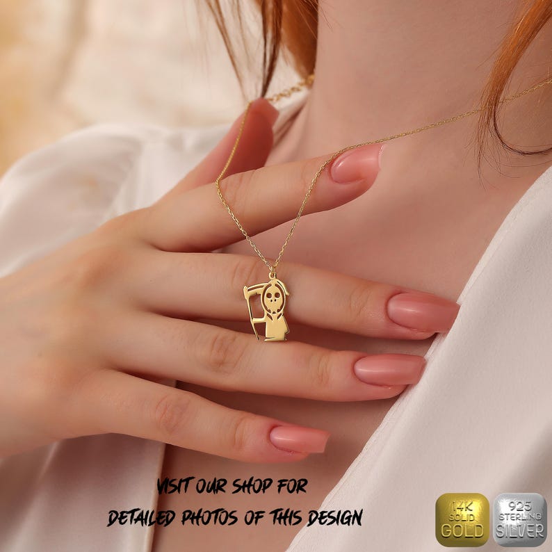 May include: Gold necklace with a pendant of a cartoon grim reaper holding a scythe. The pendant is made of solid 14k gold and the chain is made of 925 sterling silver.
