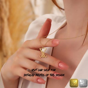 May include: A gold necklace with a pendant featuring the sigil of Baphomet, a triangular symbol with two intertwined heads. The necklace is worn by a person with their hand holding the pendant. The image includes the text "VISIT OUR SHOP FOR DETAILED PHOTOS OF THIS DESIGN" and two labels: "14K SOLID GOLD" and "925 STERLING SILVER".