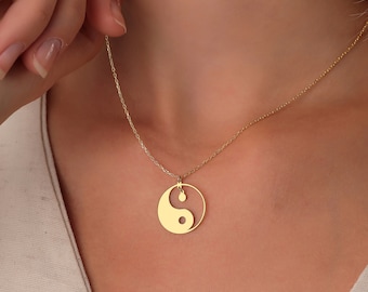 May include: A gold necklace with a yin yang pendant. The pendant is a circle with a black and white yin yang symbol inside.