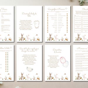 May include: A set of eight baby shower game cards with a watercolor bunny and floral design. The cards feature various games, including trivia, charades, and guessing games, with text in a soft, elegant font. The overall color scheme is cream and gold.