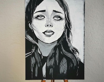 May include: Black and white portrait painting of a woman with long, wavy hair and large eyes. The artwork is displayed on a small wooden easel. The painting has a grayscale color palette.