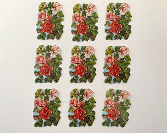 Op de afbeelding: Negen vintage papieren stickers met een bloemenmotief met roze en rode rozen op een blauwe achtergrond.