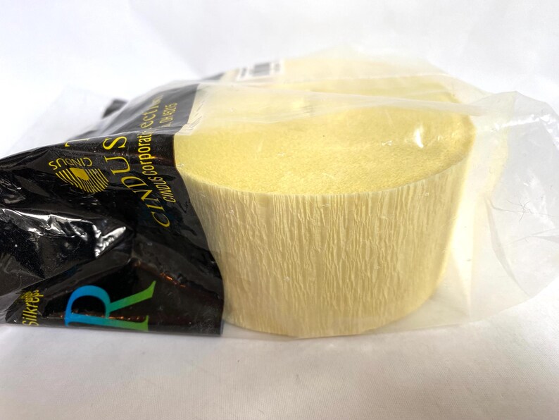 May include: A roll of light yellow crepe paper, partially visible within a clear plastic wrapper. The paper has a textured, crinkled surface. The packaging includes black and white text with the brand name "Cindus".