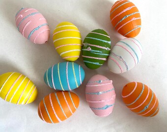 May include: A collection of ten decorated Easter eggs in various colors, including pink, yellow, green, blue, and orange. Each egg has a different pattern of stripes and swirls.