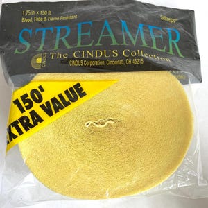 May include: A roll of yellow streamer in a clear plastic package. The package has text that reads "STREAMER" and "150' EXTRA VALUE". The streamer is 1.75 inches by 150 feet and is bleed, fade, and flame resistant.