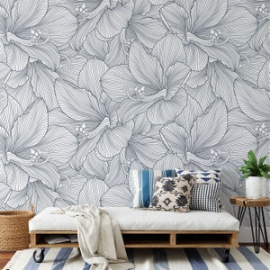 Peut inclure: Un canap&eacute; blanc avec une couverture blanche et des coussins &agrave; motifs bleus et blancs est plac&eacute; devant un mur avec un motif floral bleu et blanc.