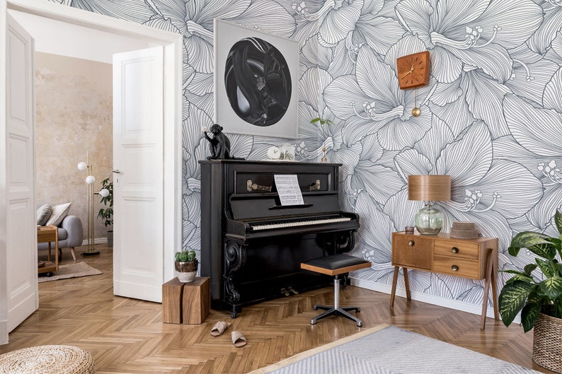 Peut inclure: Un piano &agrave; queue noir sur fond de papier peint floral. Le papier peint pr&eacute;sente un motif floral blanc et gris. Le piano a un clavier noir et blanc et un banc de piano noir. Il y a une petite plante sur un support en bois &agrave; c&ocirc;t&eacute; du piano.