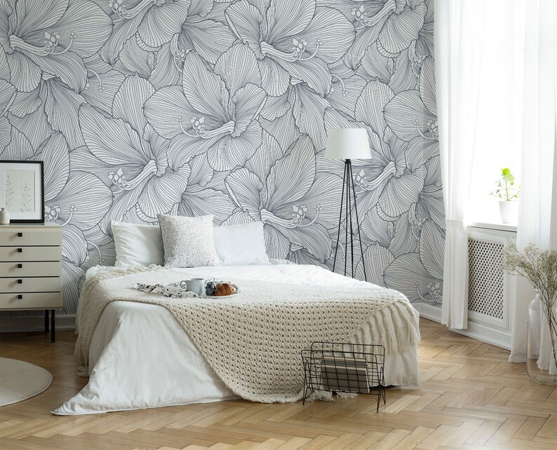 Peut inclure: Un lit blanc avec une couverture blanche et un coussin blanc dans une chambre avec un mur blanc orn&eacute; d'un papier peint floral noir et blanc.