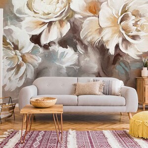 May include: A living room interior with a gray sofa, a wooden coffee table, a wooden cabinet, and a yellow knitted pouf. The wall behind the sofa is decorated with a large floral mural featuring white and brown peonies.