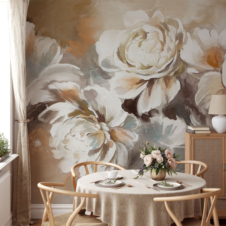 May include: A dining room with a floral wallpaper featuring large white peonies with brown and beige accents. A round table with a beige tablecloth is set with two place settings and a vase of pink flowers in the center.