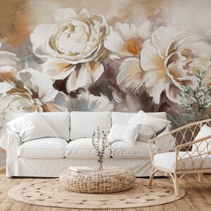 May include: A white couch and a wicker chair in a living room with a large floral wall mural featuring white and brown flowers.