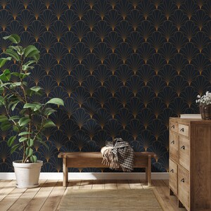 K&ouml;nnte beinhalten: Eine Holzbank mit einer braunen Wolldecke steht vor einer dunkelblauen Wand mit einem goldenen geometrischen Muster. Rechts im Bild steht eine Kommode aus Holz mit Schubladen. Der Boden ist aus hellem Holz.
