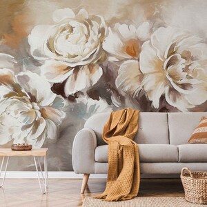 May include: A living room interior design featuring a white couch with a brown throw blanket, a woven basket, and a wooden side table. The wall is decorated with a large abstract painting of white and brown flowers.