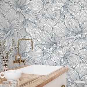 Peut inclure: Un plan de travail de cuisine blanc avec un &eacute;vier en porcelaine blanche et un robinet dor&eacute;. Le dosseret est un papier peint floral blanc et bleu avec un motif en ligne.