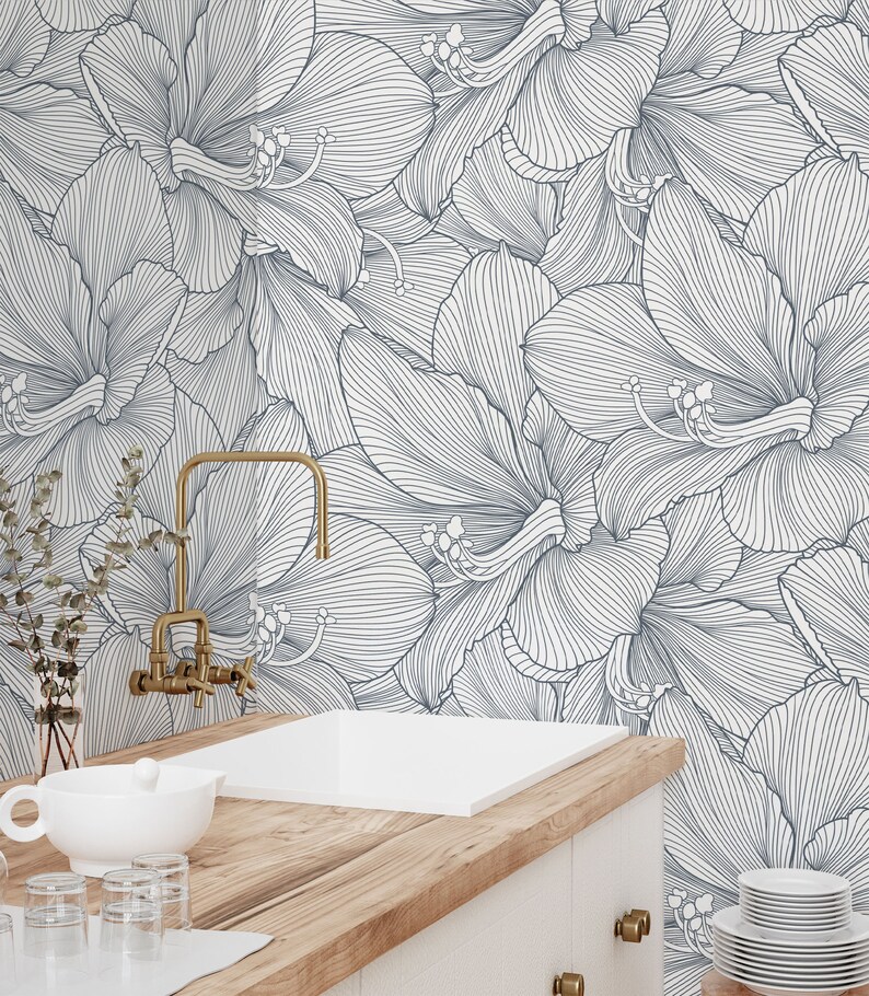 Peut inclure: Un plan de travail de cuisine blanc avec un &eacute;vier en porcelaine blanche et un robinet dor&eacute;. Le dosseret est un papier peint floral blanc et bleu avec un motif en ligne.
