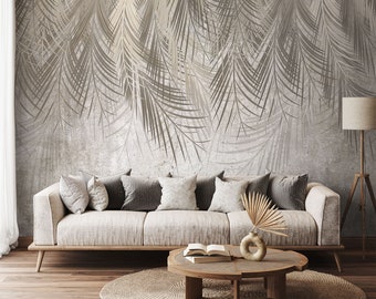 May include: A light beige sofa with a variety of throw pillows sits in front of a wall with a gray and white palm leaf pattern. A round wooden coffee table with a book and a vase with dried palm fronds sits in front of the sofa. A woven rug is on the floor.