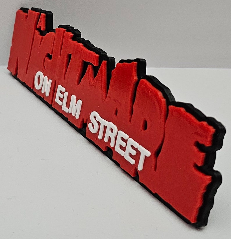 Op de afbeelding: Een "A Nightmare on Elm Street" logo, 3D-geprint in rood met een zwarte omtrek en witte letters.