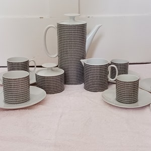 May include: A white and black chequered porcelain tea set with a teapot, creamer, sugar bowl, and six cups and saucers.