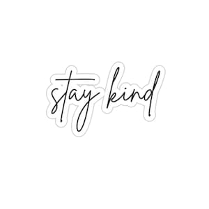 May include: Black and white handwritten text on a white background that reads "stay kind".