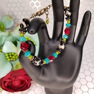May include: A colorful beaded bracelet with black and white patterned beads, red and turquoise glass beads, and gold accents.