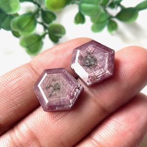 May include: Two hexagonal pink and purple gemstones with a faceted design.
