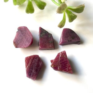 Peut inclure: Cinq pierres précieuses de rubis rose brutes. Les pierres sont de formes et de tailles variées, avec une finition naturelle non polie.