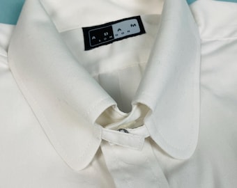 May include: White dress shirt with a collar and button closure. The shirt has a label that reads "ADAM LONDON".