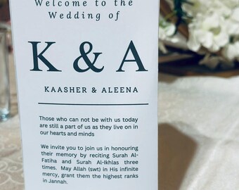May include: A white wedding program with black text. The program reads "Welcome to the Wedding of K & A, Kaasher & Aleena." Additional text includes a request to respect privacy and refrain from sharing photos or videos.