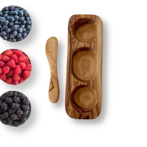 May include: A wooden serving dish with three separate bowls, perfect for serving snacks or dips. The dish is made of olive wood and has a natural, rustic finish.