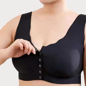 May include: Black front-closure bra with a scoop neckline and wide straps. The bra features a series of small, dark buttons down the center. The bra is made of a smooth, matte fabric.