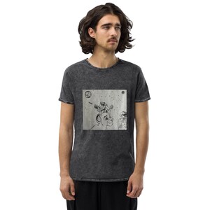 Könnte beinhalten: Ein schwarzes T-Shirt mit einem ausgewaschenen Look zeigt einen grafischen Druck eines Löwen mit einem kleineren Löwen auf seinem Kopf. Die Grafik ist in Schwarzweiß gehalten und zeigt die Löwen in einer Weltraumumgebung mit Sternen und Planeten.