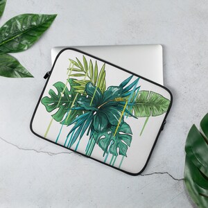 Könnte beinhalten: Eine weiße Laptoptasche mit einem tropischen Druck mit grünen und blauen Blättern, einer großen grünen Hibiskusblüte und gelben Akzenten.