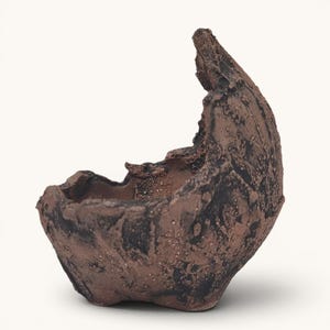 May include: A small, hand-formed ceramic bowl with a highly textured, rugged surface. The exterior features a dark brown and black mottled finish with deep crevices and an uneven, jagged rim that rises higher on one side, creating a crescent shape.