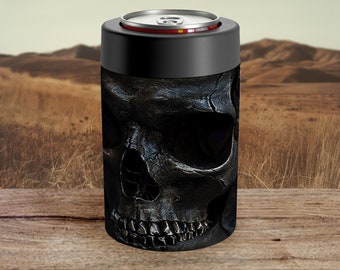 Puede incluir: Un enfriador de latas negro con un diseño detallado de calavera. El enfriador tiene una parte superior negra y un borde plateado. El diseño de la calavera es texturizado y parece metálico. El fondo muestra un paisaje con hierba seca y montañas.
