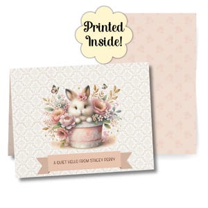 Op de afbeelding: Wenskaart met een witte konijn omringd door roze en perzik bloemen. De kaart heeft een bloemenpatroon achtergrond en een banner met de tekst "A Quiet Hello From Stacey Perry". Een apart label zegt "Printed Inside!"