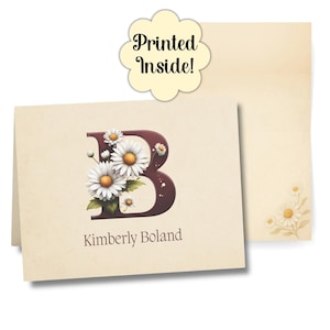 Puede incluir: Juego de papelería color crema con una gran letra "B" burdeos adornada con margaritas blancas y el nombre "Kimberly Boland". El juego incluye una tarjeta y un sobre, con el texto "Printed Inside!" en una etiqueta decorativa.