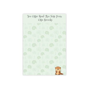 May include: A rectangular notepad with a light green background and a repeating pattern of light green seashell shapes and sprigs. The notepad has the text "You Otter Read This Note From Otis Brooks" at the top and a cartoon otter at the bottom.