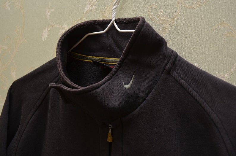 May include: A dark gray zip-up jacket with a silver Nike swoosh logo on the chest.