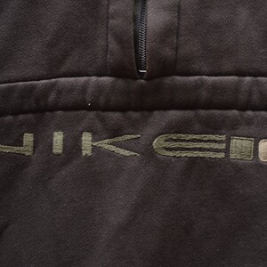 May include: A black sweatshirt with a green embroidered Nike logo and a zipper at the neck.